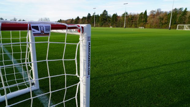 Close-up of a football goal post on an artificial turf field, featuring the "Mark Harrod" branding on the frame.