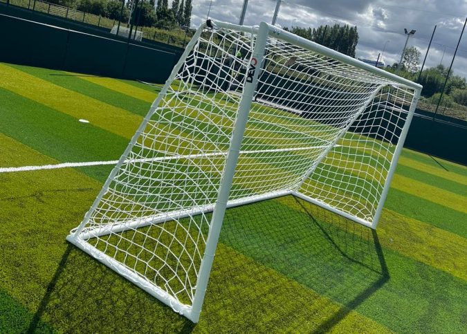 Portable football goal on a synthetic pitch, positioned for training or match setup as part of proper goal post maintenance.